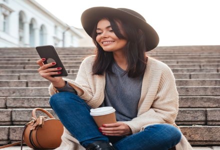woman holding a phone and drinking coffee